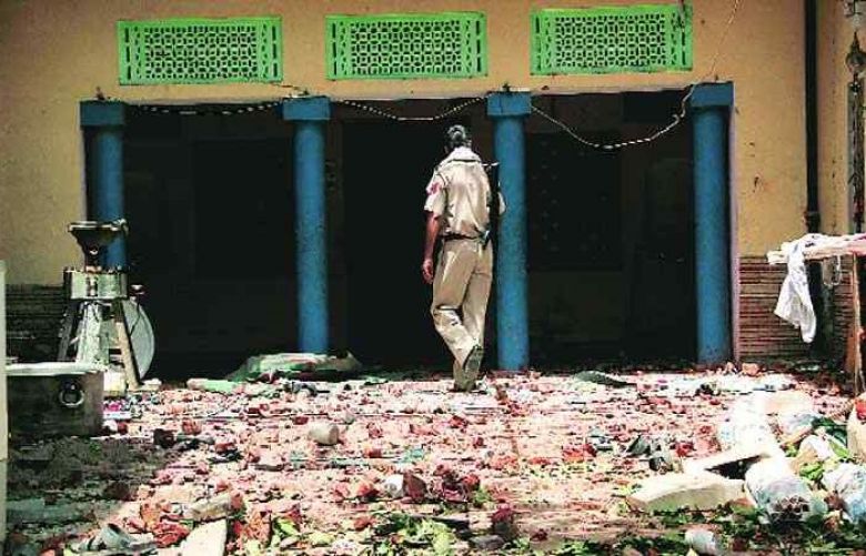 An Indian policeman inspects the burnt mosque under construction