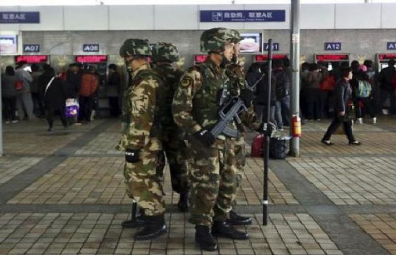Armed paramilitary policemen stand guard next to train ticket booths