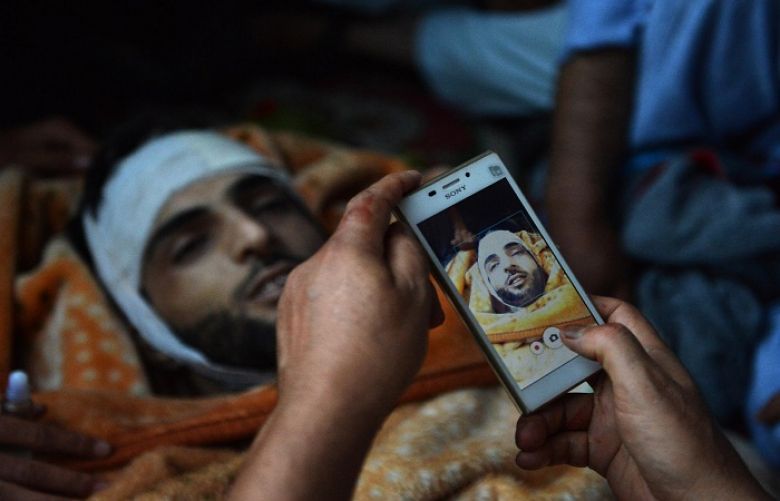 In this photograph taken on July 9, 2016, Kashmiri mourners take photographs of the body of Burhan Muzaffar Wani.