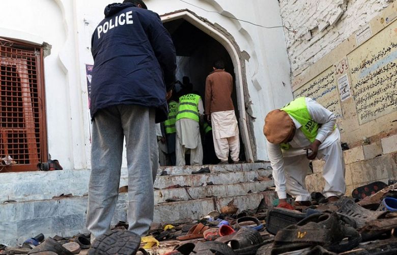 Police and volunteers gather evidence following a bomb attack at an imambargah in Shikarpur.