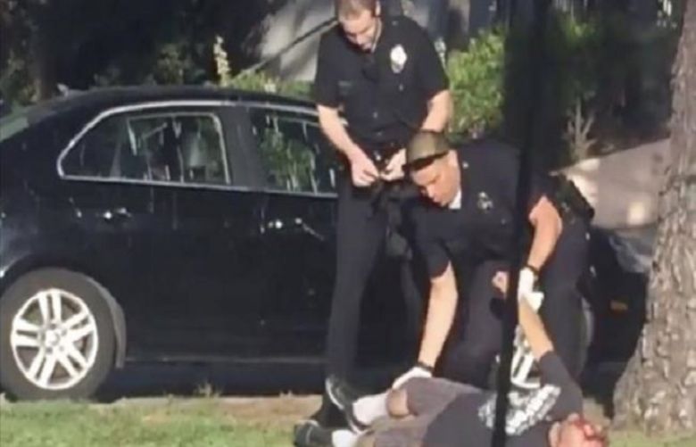 An image grab of a video that shows two LAPD officers shot a man in the head and then handcuff him.