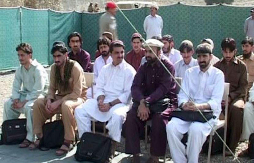Afghan nationals wait at a military camp before being handed over to authorities in Afghanistan on Friday.