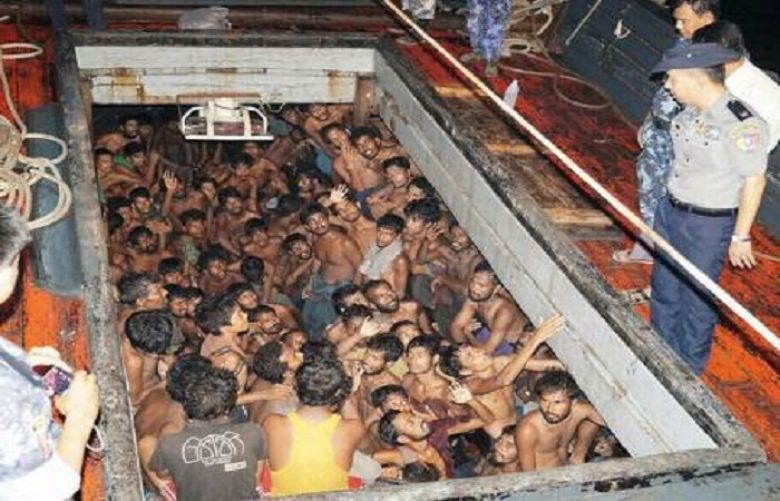 Myanmar police officers speak to would-be migrants below deck on a fishing boat off the western coast of Rakhine