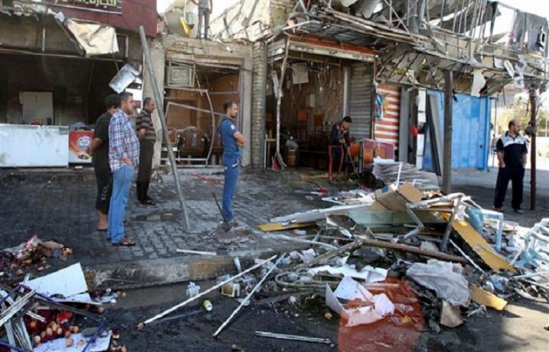 Iraqis stand at the site of a car bomb explosion at the Bab al-Mudham area in the capital, Baghdad, on April 3, 2015.
