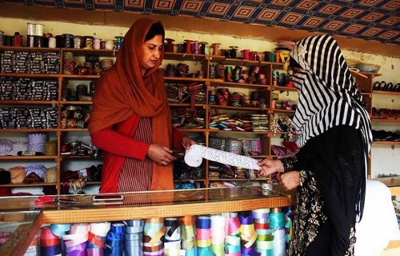 Pakistani Kashmiri woman Sara Rasheed (L) sells border trim cloth to a customer at her shop  in the women&#039;s market.
