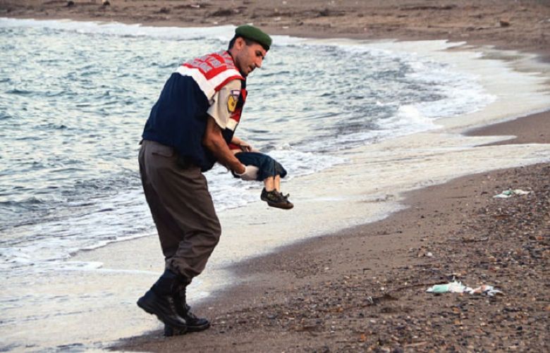A Turkish border guard carries the body of a migrant child after a number of migrants died and a smaller number were reported missing after boats carrying them to the Greek island of Kos capsized, near the Turkish resort of Bodrum