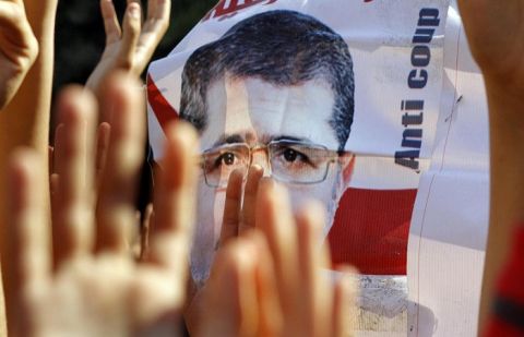 Supporters of Egypt's ousted President Mohammed Morsi raise his poster and their hands with four raised fingers, which has become a symbol of the Rabaah al-Adawiya mosque