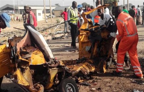 This file photo taken on October 29, 2016 shows emergency personnel standing near the wreaked remains of a vehicle ripped apart following two bombings in Nigeria's northeastern city of Maiduguri.