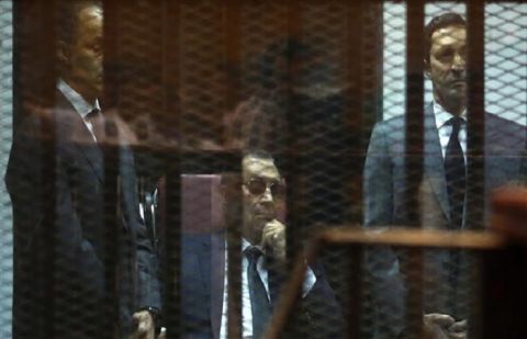 Ousted Egyptian president Hosni Mubarak (C) sits in the defendant’s cage in between his sons Gamal (L) and Alaa as they listen to the verdict in their hearing in a retrial for embezzlement on May 9, 2015 in Cairo