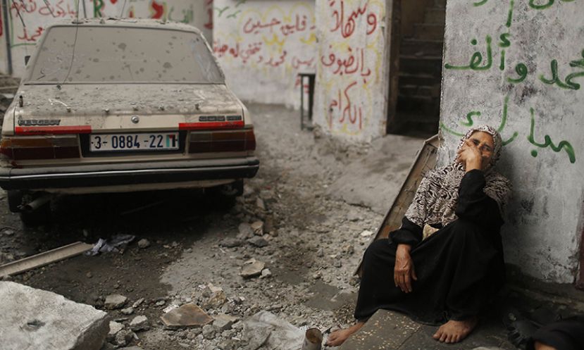 A Palestinian woman sits in a debris-strewn street as she looks at houses which witnesses said were damaged in an Israeli air strike that killed two children, in the northern Gaza Strip.