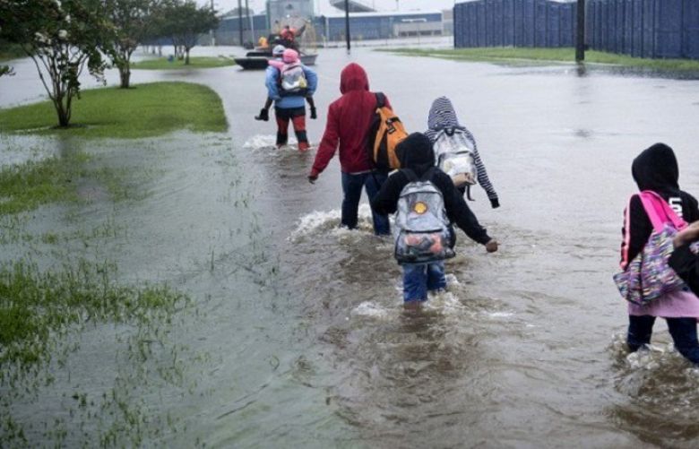 People walk to a Harris County Sherif air boat while escaping a flooded neighborhood during the aftermath of Hurricane Harvey on August 29, 2017 in Houston, Texas. Floodwaters have breached a levee south of the city of Houston, officials said Tuesday, urging residents to leave the area immediately.