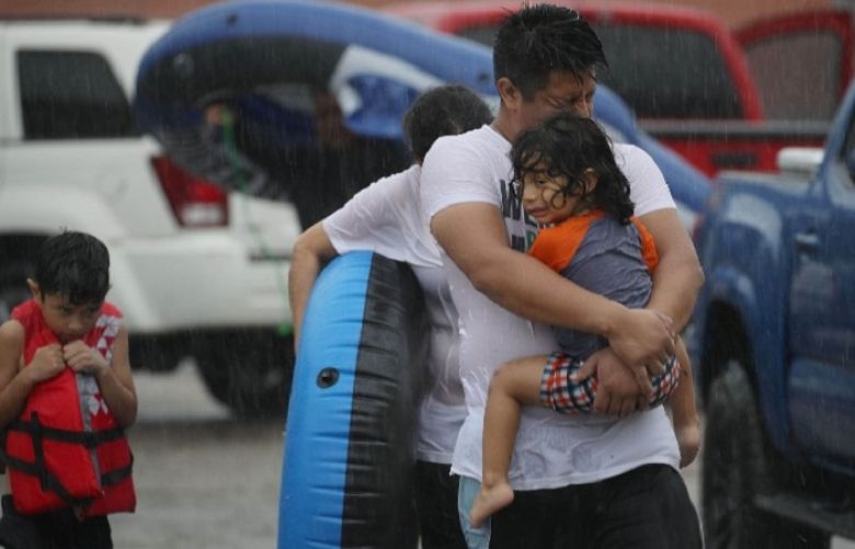 Mario Qua holds Wilson Qua as they evacuate their flooded home after the area was inundated with flooding from Hurricane Harvey in Houston, Texas.