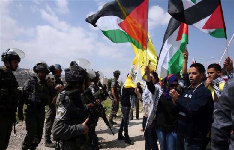 In this photo Palestinians and foreign demonstrators are waving the national flag of Palestine in front of Israeli forces during an anti-Tel Aviv march near the West Bank town of Abu Dis, March 17, 2015.