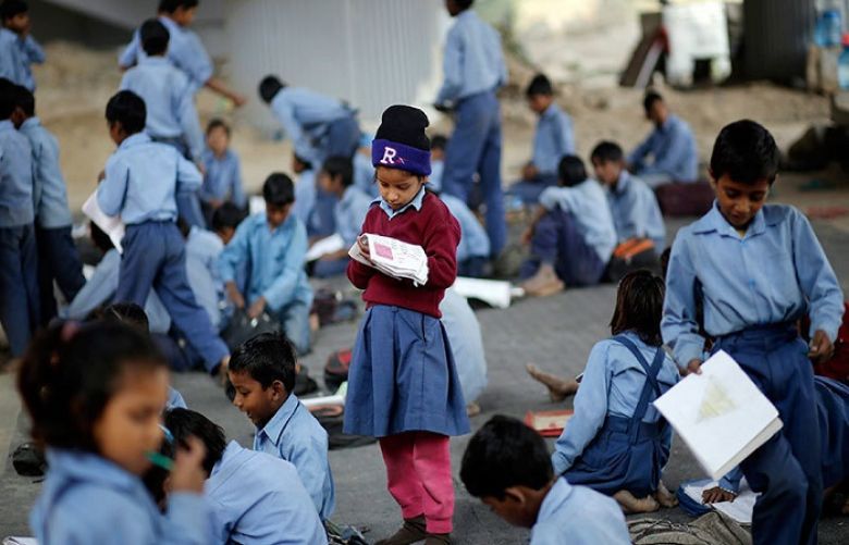 A schoolgirl reads from a textbook at an open-air school in New Delhi November 20, 2014.