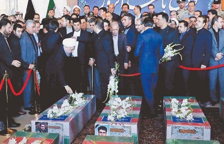 A picture provided by the Iranian presidency shows President Hassan Rouhani touching a coffin during the funeral on Friday of the victims of twin attacks in Tehran earlier in the week.