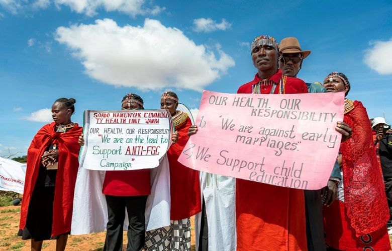 Massai community members hold banners with messages, such as &quot;We are against early marrigae&quot;.