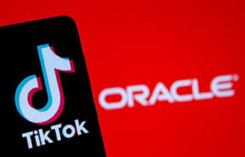 A smartphone with the Tik Tok logo is seen in front of a displayed Oracle logo
