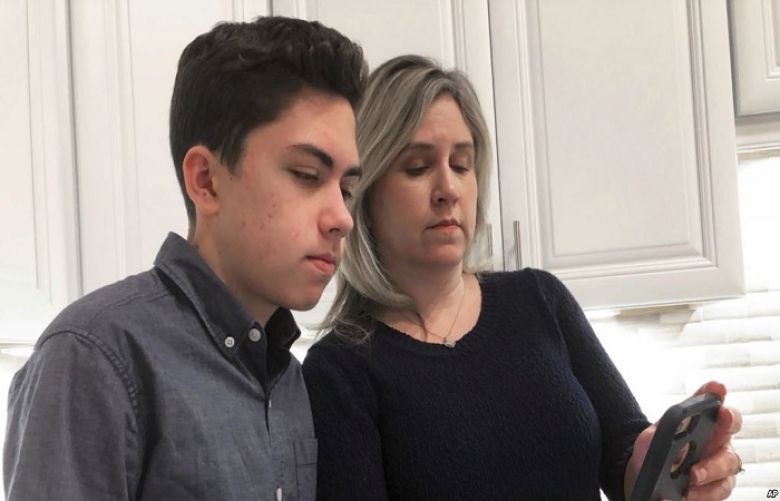Grant Thompson and his mother, Michele, look at an iPhone in the family&#039;s kitchen in Tucson, Ariz., Jan. 31, 2019. Apple has released an iPhone update to fix a FaceTime flaw that Grant was credited with spotting.