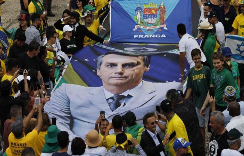 People hold a banner with a photo of Brazil&#039;s former army captain Jair Bolsonaro before the swearing-in ceremony, in front of the Planalto palace in Brasilia, Jan. 1, 2019.