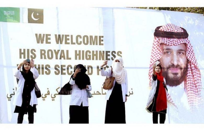 Women posing for selfies with signboard erected to welcome Saudi Crown Prince Mohammad in Islamabad on Saturday.