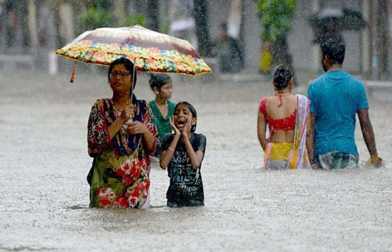 Indians wade through a flooded street during heavy rain showers in Mumbai.