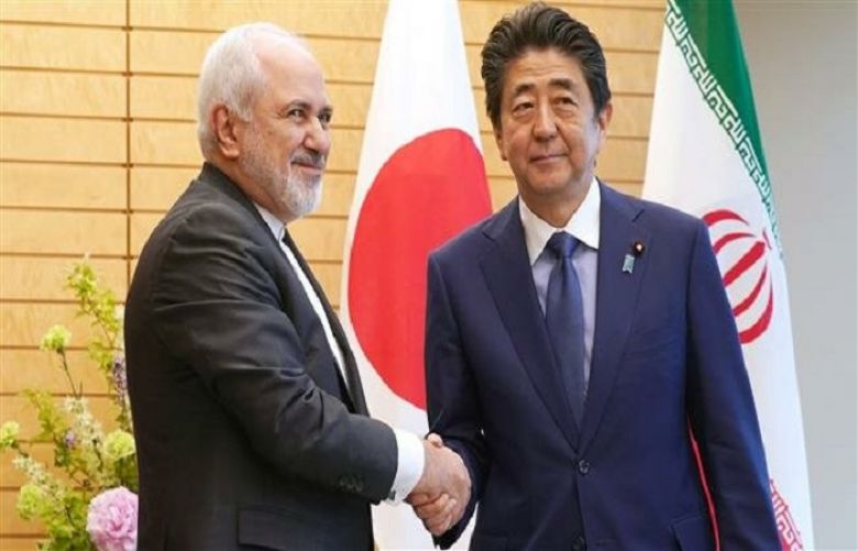Iran’s Foreign Minister Mohammad Javad Zarif (L) shakes hands with Japanese Prime Minister Shinzo Abe in Tokyo.