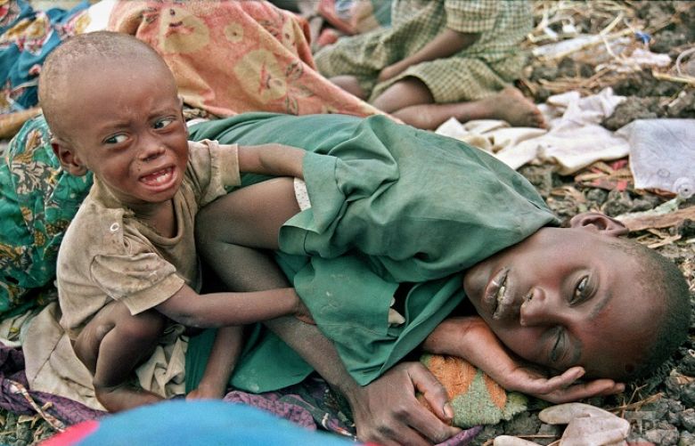 A Rwandan Hutu refugee child desperately tries to waken his mother from a diseased sleep in the Munigi camp outside Goma, in Zaire, now known as Congo on July 27, 1994. 