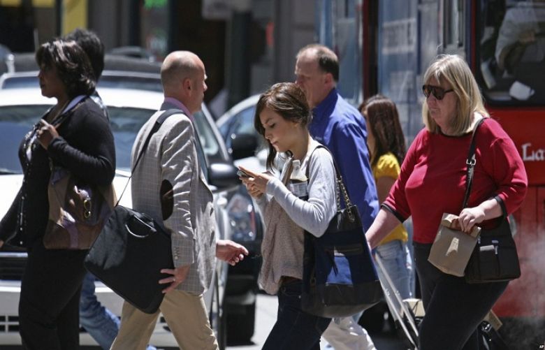 A woman sends a text message while walking across the street in San Francisco, June, 29, 2010.