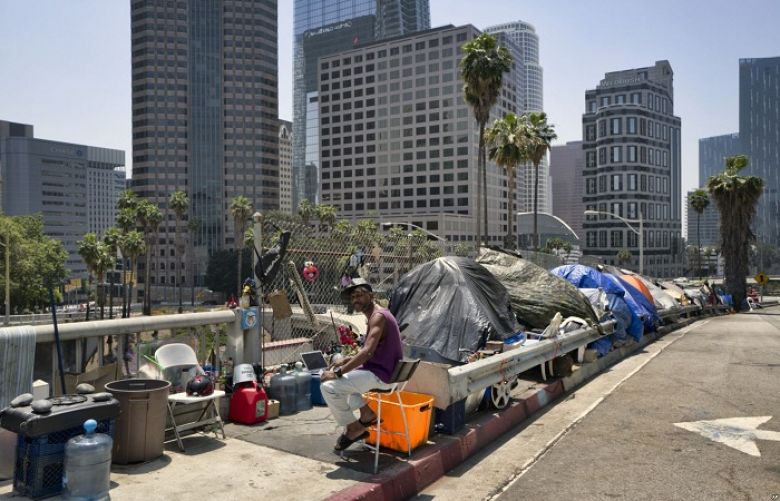 A homeless man sits at his street-side tent along Interstate 110 along downtown Los Angeles&#039; skyline, May 10, 2018. Thousands of homeless people sleep on the streets of Los Angeles County.