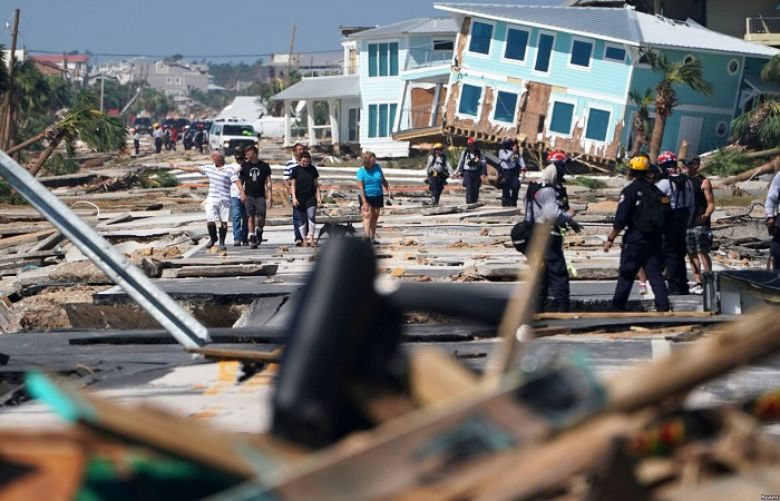 First responders and residents walk along a debris-littered street following Hurricane Michael, in Mexico Beach, Florida, Oct. 11, 2018.