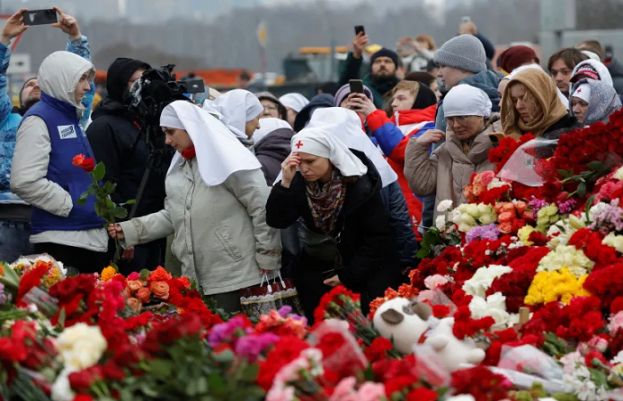 People lay flowers at a makeshift memorial outside the Crocus City Hall concert venue near Moscow