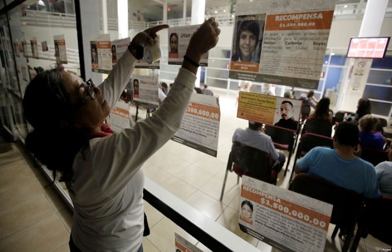 A woman attaches fliers with the photographs and details of missing persons to the glass windows of the attorney general&#039;s office, during World Day against Trafficking in Persons, in Ciudad Juarez, Mexico, July 30, 2018.