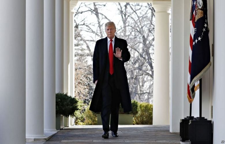 President Donald Trump waves as he walks through the Colonnade from the Oval Office of the White House on arrival to make an announcement.