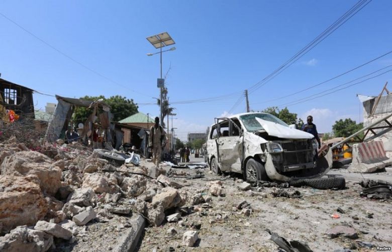 Somali policemen look at the wreckage of a destroyed car at the scene of a suicide attack at a checkpoint outside the main base of an African Union peacekeeping force in the Somali capital Mogadishu, Jan. 2, 2017.