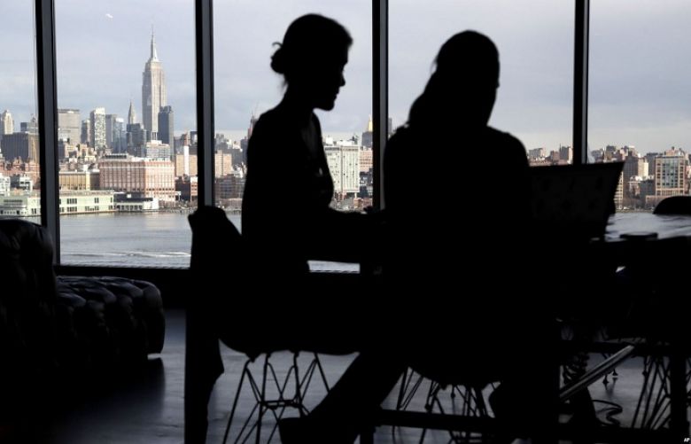 The New York City skyline is seen at a distance as two women are seen on their laptops in a building in Hoboken, New Jersey, Jan. 23, 2018. With privacy breaches on the rise, there is a growing push for greater online protection of consumers.