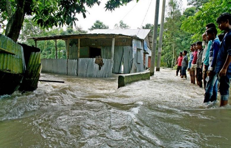 Bystanders look on as floodwaters rage near a house in Kurigram, northern Bangladesh on August 14.