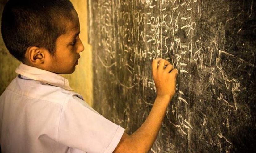 A boy practicing math on a blackboard during a lecture at Jufelhurst School in Karachi.