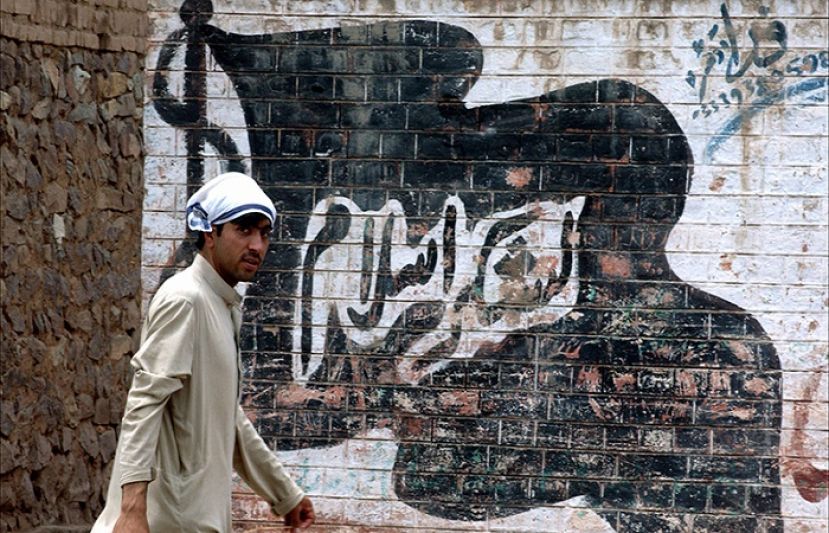 This picture shows a man walking past a wall painted with the flag of the outlawed group Lashkar-i-Islam.