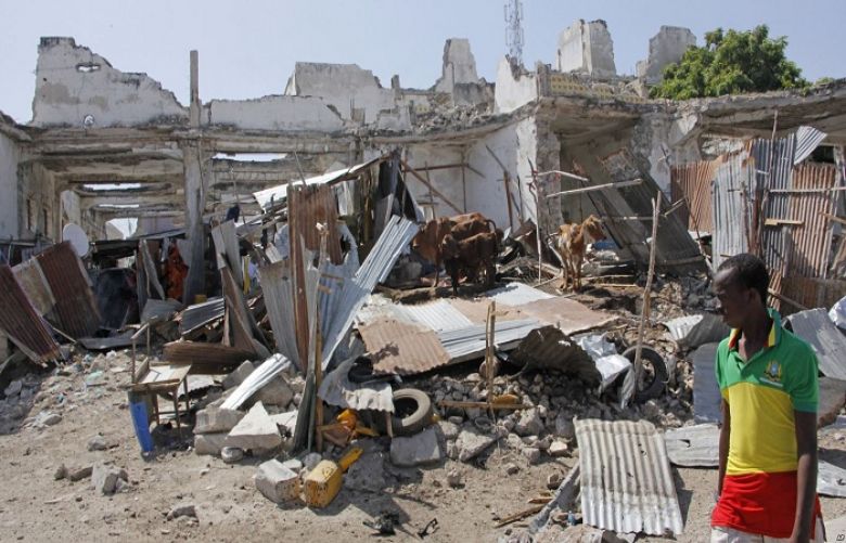 A man walks near destroyed buildings after a bomb blast in the capital city of Mogadishu, Somalia, Dec. 22, 2018. Police say a suicide car bomb exploded near the presidential palace killing and wounding a number of people.