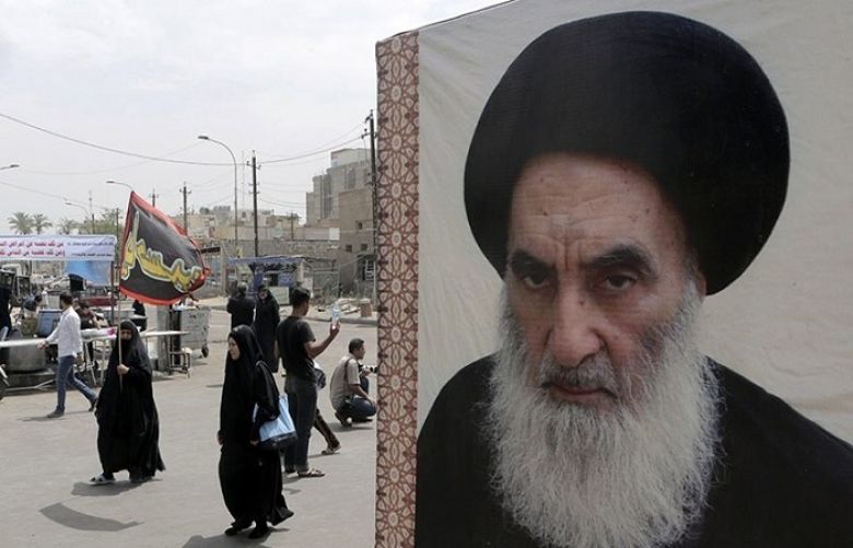 In this May 22, 2014 file photo, Shia pilgrims pass a poster of Shia spiritual leader Grand Ayatollah Ali al-Sistani, as they head to the shrine of Imam Moussa al-Kadhim in Baghdad, Iraq.