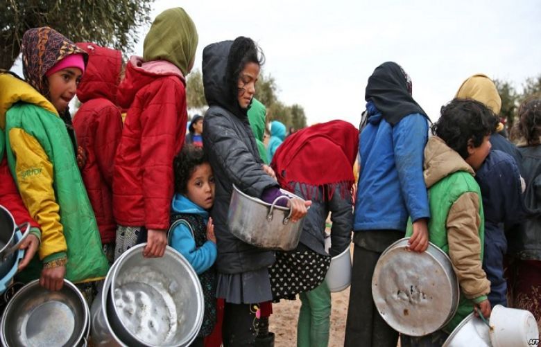 Syrian children queue to receive food distributed by humanitarian aid workers at a makeshift camp for displaced people, near the village of Yazi Bagh, Feb. 7, 2018.