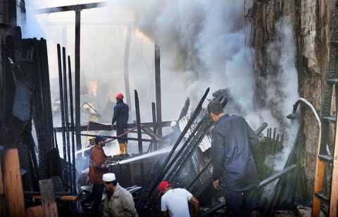 Men salvage wood while fire fighters extinguish fire which erupted in Haji Camp Timber Market. 
