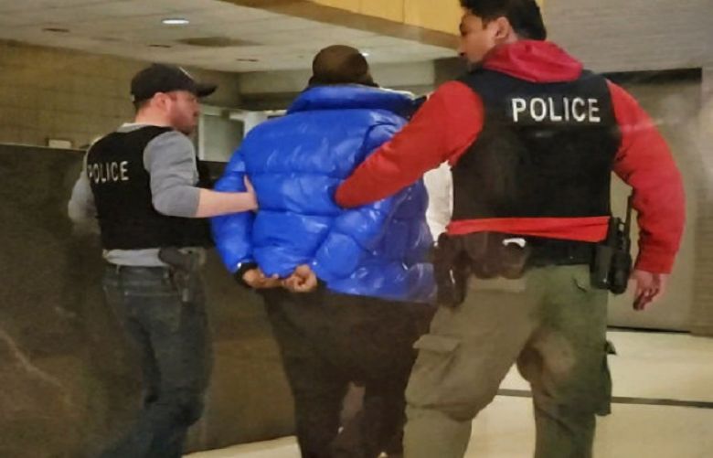 R. Kelly is escorted by police in custody at the Chicago Police Department&#039;s Central District Friday night.