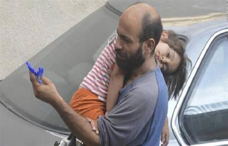 A picture, posted on social media by Norwegian activist Gissur Simonarson, shows a Syrian refugee selling pens on the streets of Beirut as he holds his sleeping daughter.