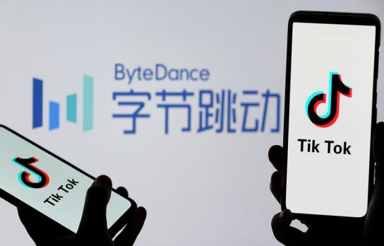 Tik Tok logos are seen on smartphones in front of a displayed ByteDance logo