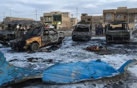 A picture taken with a mobile phone on February 16, 2017 shows burnt vehicles at the scene of a massive car bomb which killed dozens in a used car market in southern Baghdad