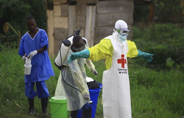In this photo taken Sept 9, 2018, a health worker sprays disinfectant on his colleague after working at an Ebola treatment center in Beni, DRC.